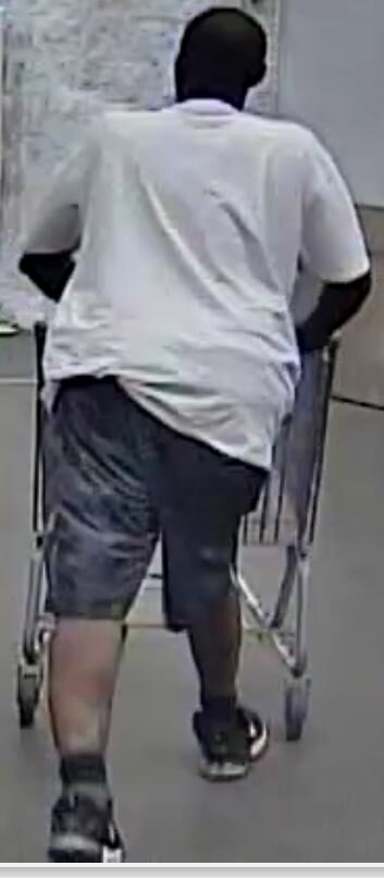 The backside of the suspect, seen wearing a white t-shirt and black shorts.